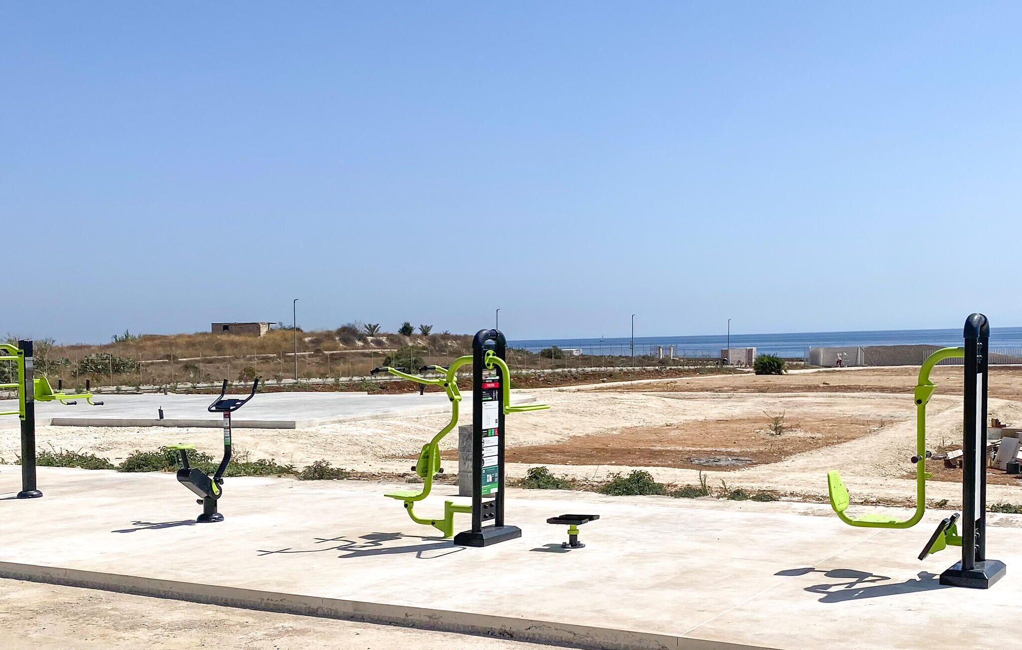 Outdoor exercise equipment with a clear view of the beach and ocean in the background.