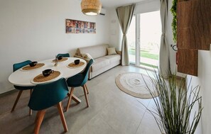 A modern living room with a dining area, a sofa, and a large window with curtains.