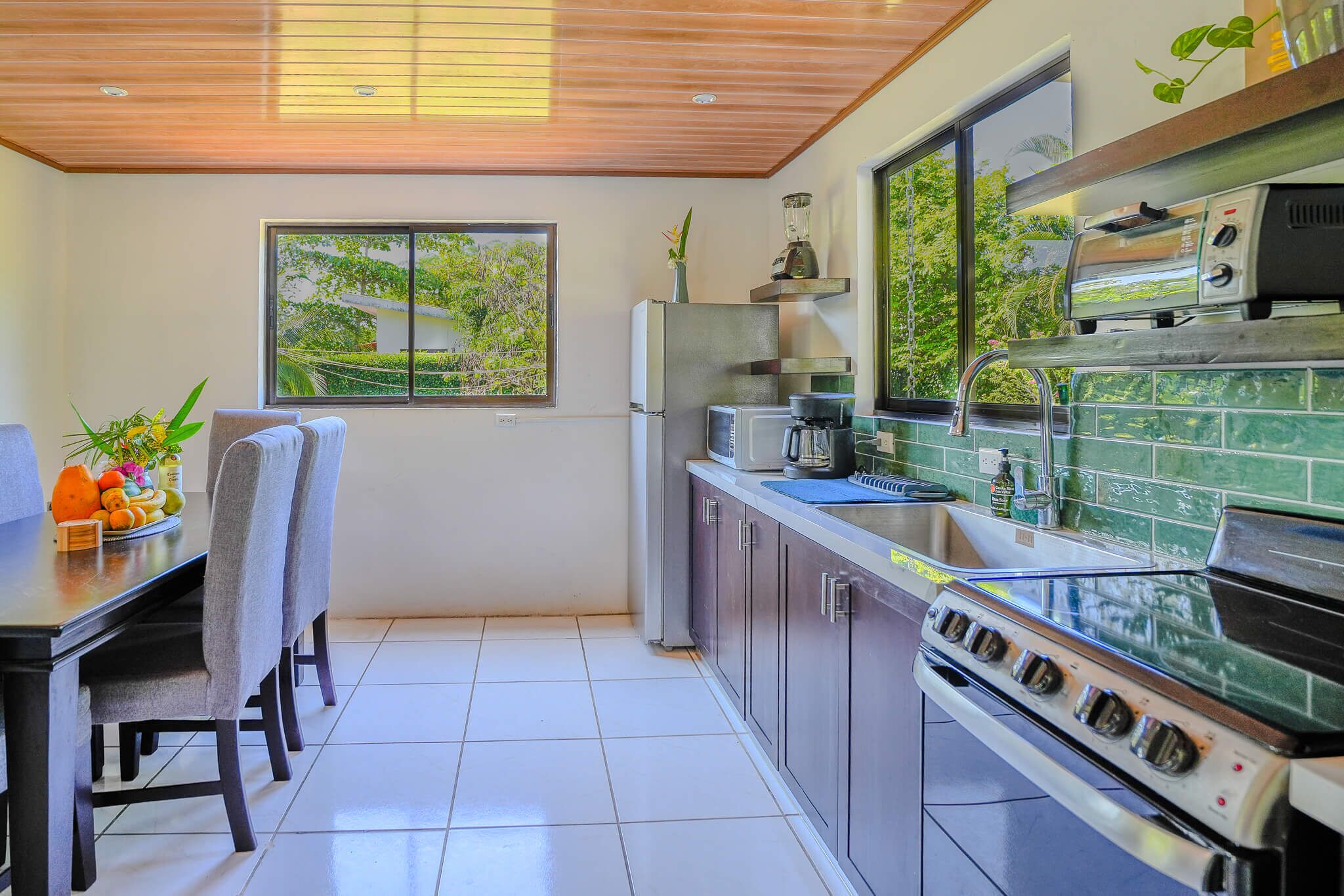 Una cocina moderna con horno integrado, refrigerador y ventana con vista a follaje.