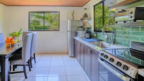 Une cuisine moderne dotée d’un four encastré, d’un réfrigérateur et d’une fenêtre donnant sur un espace verdoyant.