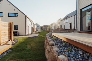 Zona residencial con casas modernas, un sendero estrecho y una terraza de madera.
