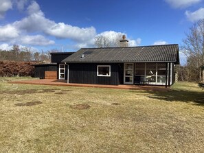 A black building with a metal roof, a chimney, and a deck area.