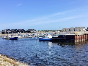 A marina with boats docked, a pier, and buildings with signage.