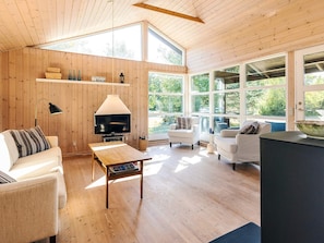A spacious living room with wooden walls, a television, a coffee table, and a sofa.