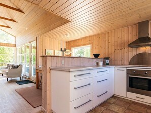 A wooden-paneled kitchen with a large island, stainless steel appliances, and a view of the outdoors. - 4 Person Holiday Home in Hals (Hals)