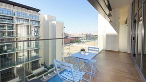 A balcony with a pool, glass railings, and a table with chairs.