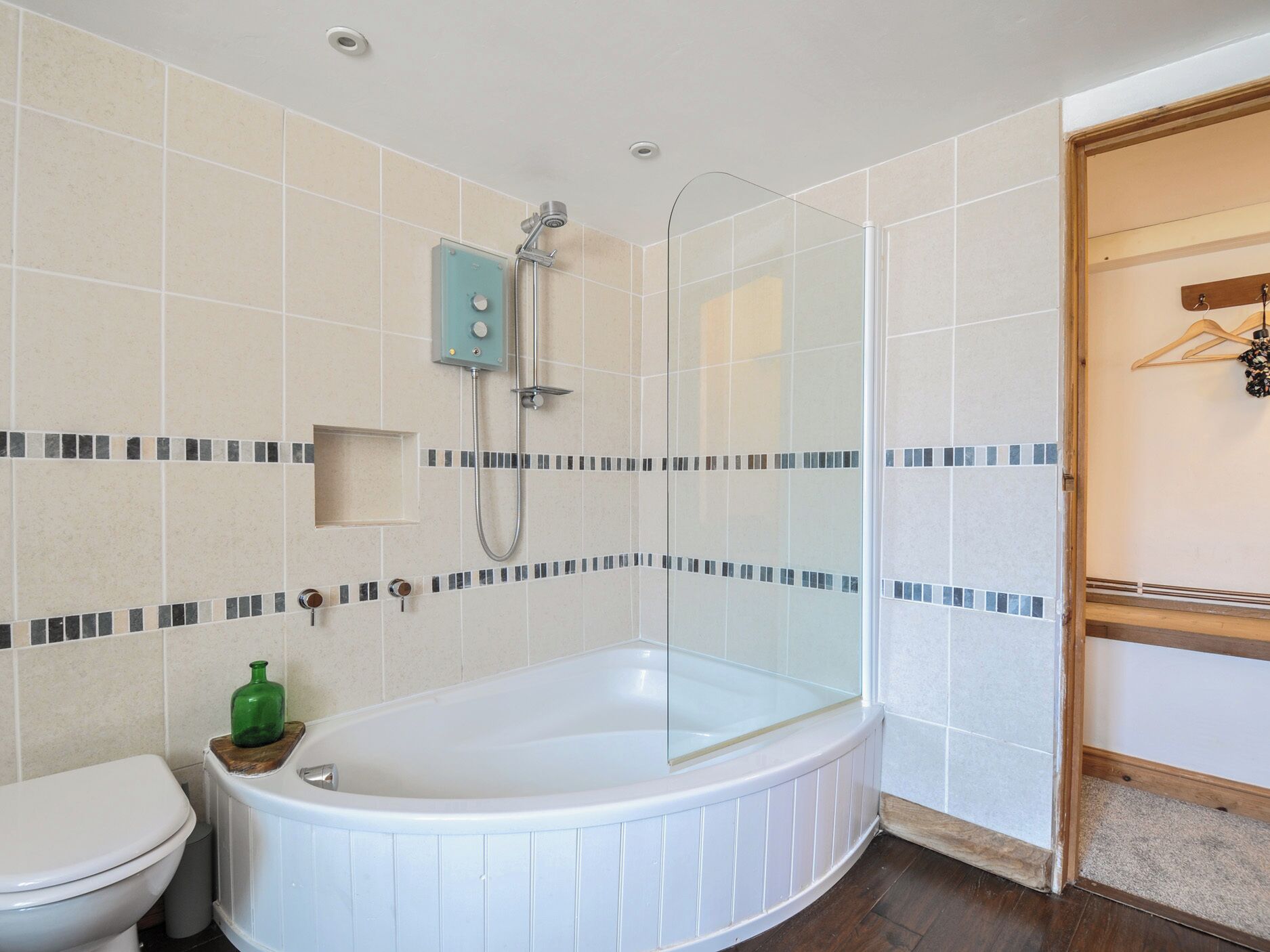 A bathroom with a glass-enclosed shower, a white bathtub, and a toilet.