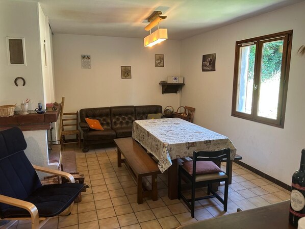 Un comedor acogedor con una mesa lista para dos personas, un sofá y una silla.