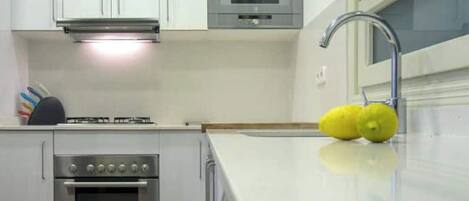 Eine moderne Küche mit weißen Schränken, einem Edelstahlbackofen, einer Mikrowelle und einem Spülbecken mit Armatur.