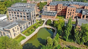 A modern building complex with multiple floors, a central courtyard, and a small pond.