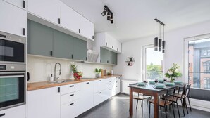 A modern kitchen with white cabinets, a wooden countertop, and a dining area with a table set for four.