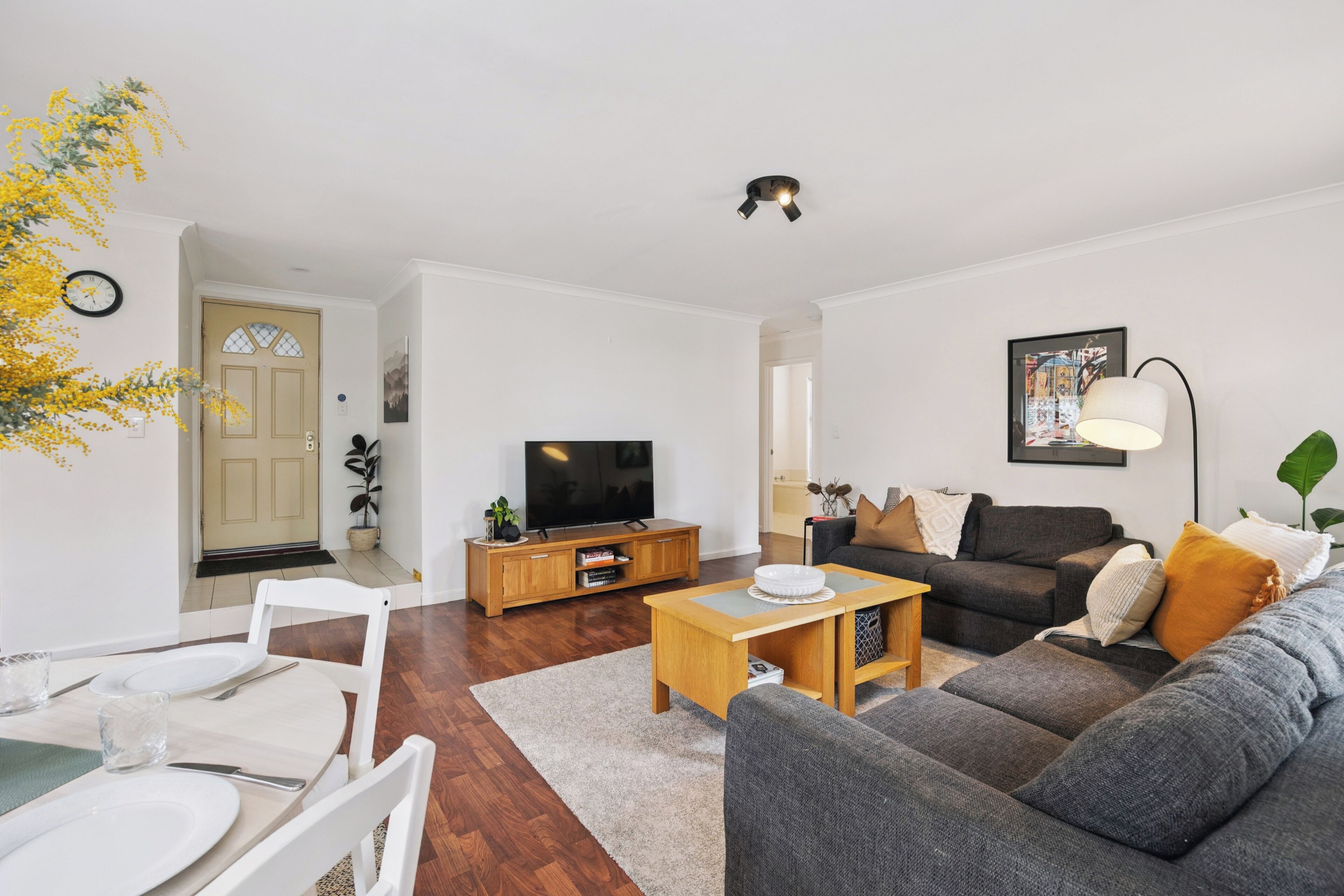 A modern living room with a sofa, coffee table, TV, and dining area.