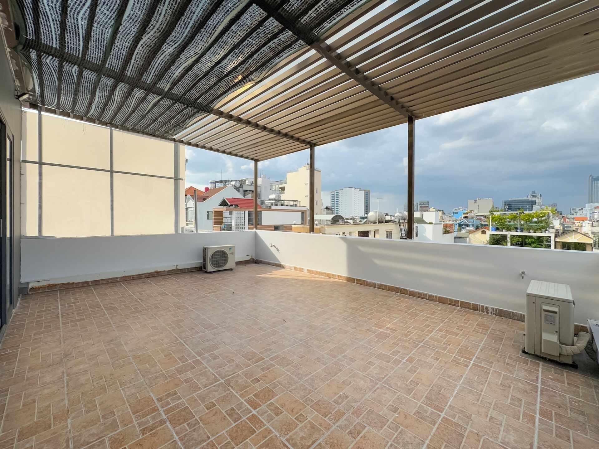 A rooftop terrace with a tiled floor, a pergola, and an air conditioning unit.