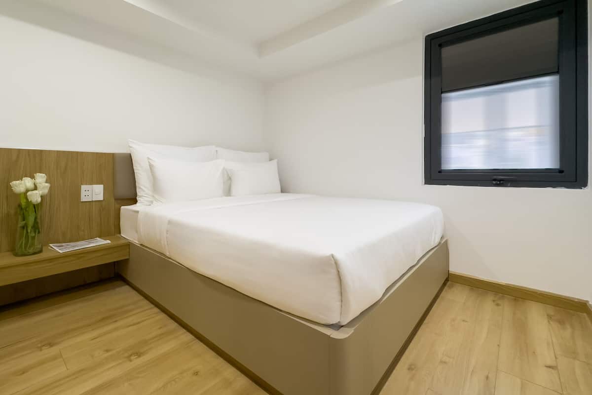 Une chambre à coucher moderne avec un lit, une table de chevet, un vase de fleurs et une fenêtre.