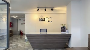 Una recepción de hotel con diseño moderno, un cartel que dice "nest DC Apart - Hotel" y un extintor en la pared.
