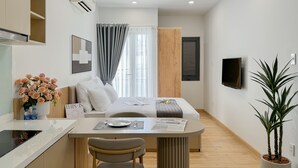 Una habitación moderna y luminosa, con kitchenette, zona de comedor y cama.