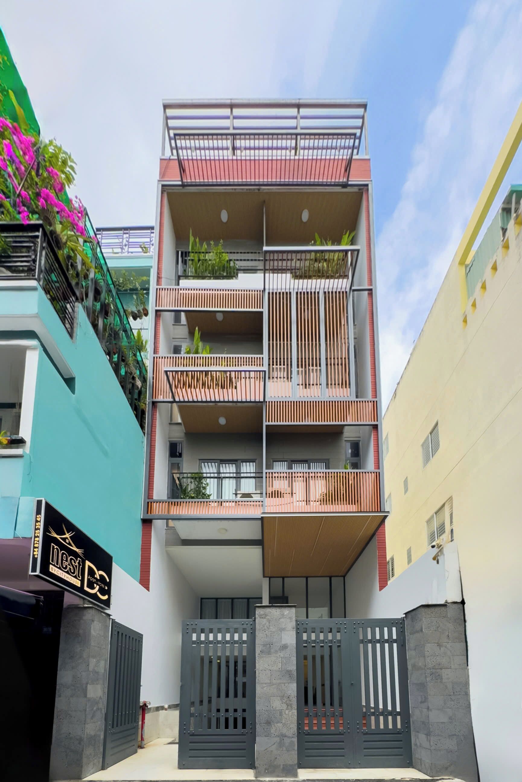 A multi-story residential building with balconies, a gated entrance, and a sign indicating a business on the ground floor.