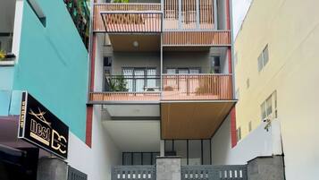A multi-story residential building with balconies, a gated entrance, and a sign indicating a business on the ground floor.