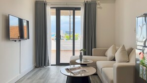 Una sala de estar moderna con una televisión de pantalla plana, un sofá, una mesa de centro y vistas de la ciudad a través de un ventanal.