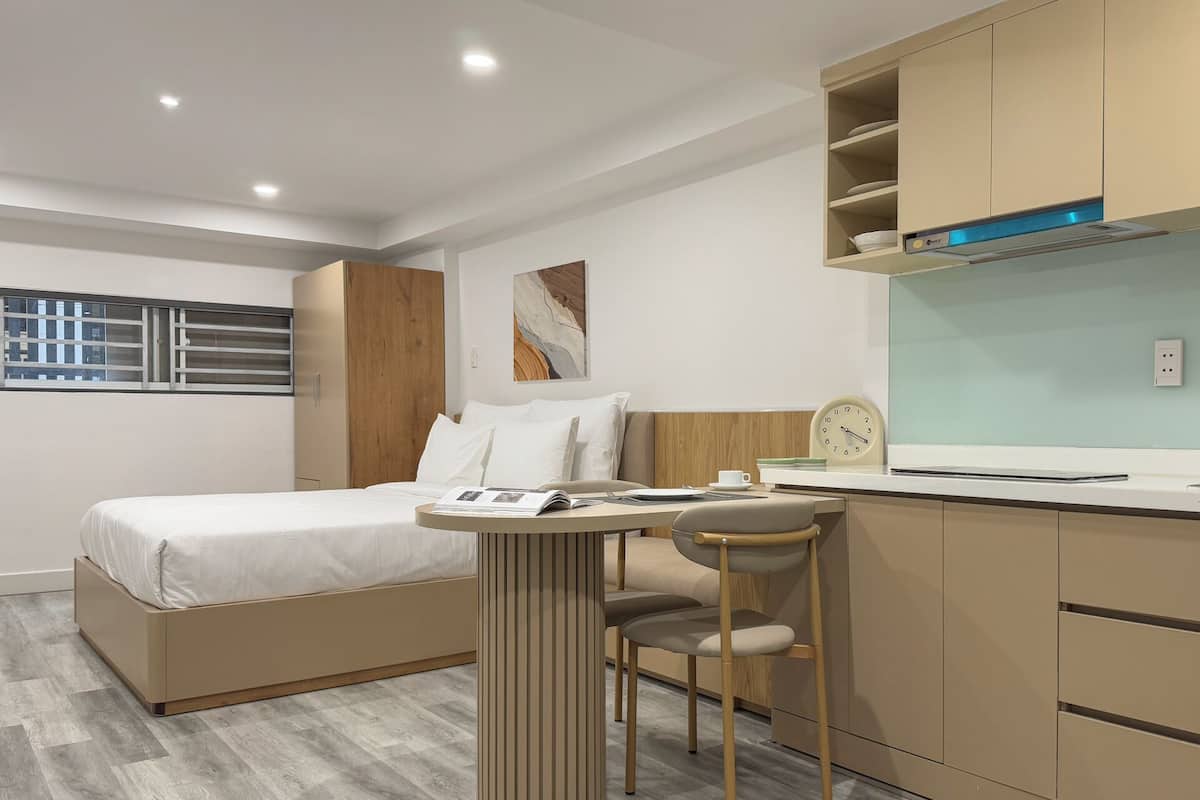 Une chambre d’hôtel moderne équipée d’un lit, d’un bureau, d’une chaise et d’une kitchenette.