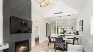 A modern living room with a fireplace, a dining area, and a kitchen in the background. - Skyline Loft | Capitol Peak Lodge #3323 | 1B/1B (Snowmass Village)