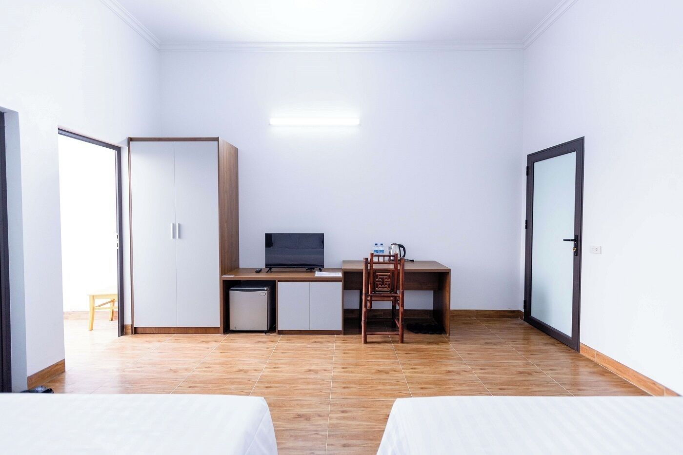 A small, well-lit room with a desk, chair, and two beds.