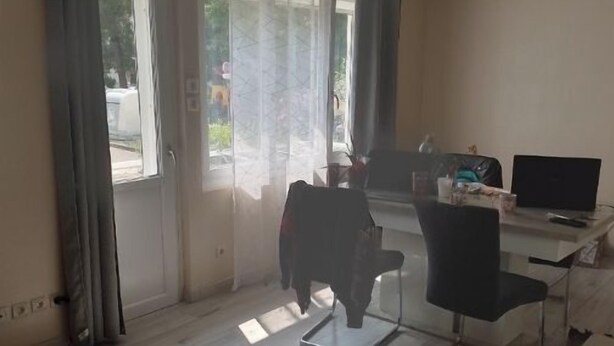 Ett rum med en stor skjutdörr av glas, ett skrivbord med en dator och en stol.