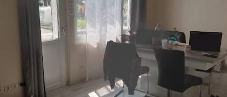 A room with a large sliding glass door, a desk with a computer, and a chair.