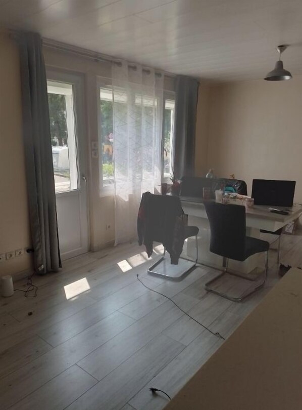 Una habitación con un amplio ventanal corredero, un escritorio con ordenador y una silla.