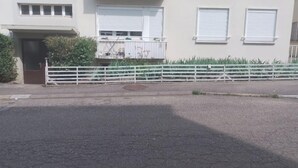 En flervåningsbyggnad med bostäder, balkonger, en grind vid entrén och ett vitt staket.