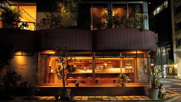 A hotel with a modern design, featuring a large glass facade, outdoor seating area with potted plants, and a visible restaurant interior. - SOIL Nihonbashi Hotel (Tokyo)