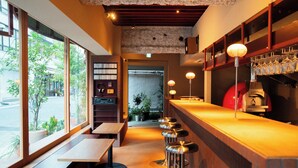 A restaurant interior with wooden tables, bar stools, and a counter with hanging glasses. - SOIL Nihonbashi Hotel (Tokyo)