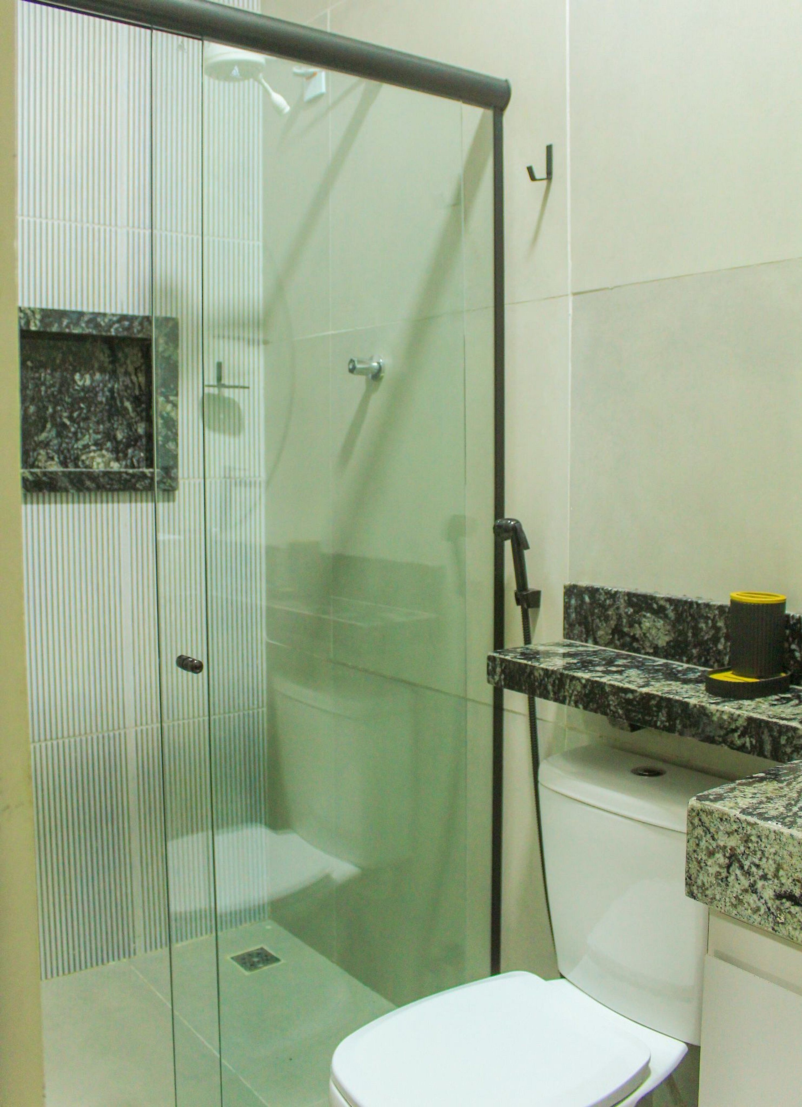 A bathroom with a glass-enclosed shower, a toilet, and a granite countertop.