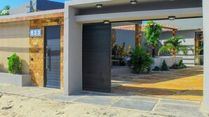 A modern building with a stone facade, a black door, and a number '533' sign. - Casa Bons ventos (Cruz)