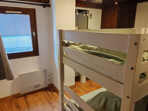 Un lit superposé avec une fenêtre, un radiateur et un miroir.
