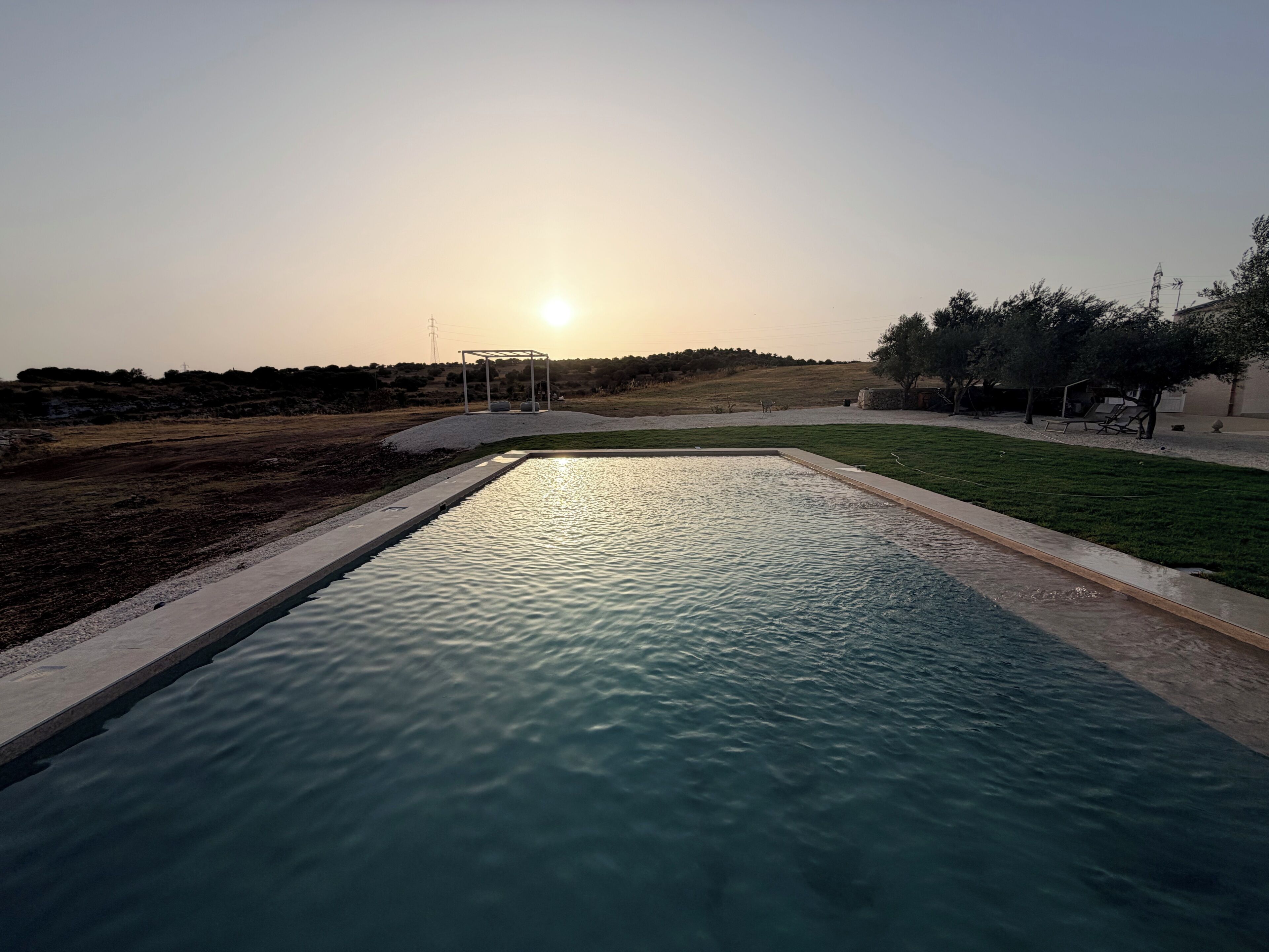 A swimming pool with a clear view of the sunset in the background.