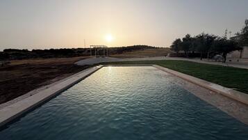 A swimming pool with a clear view of the sunset in the background.