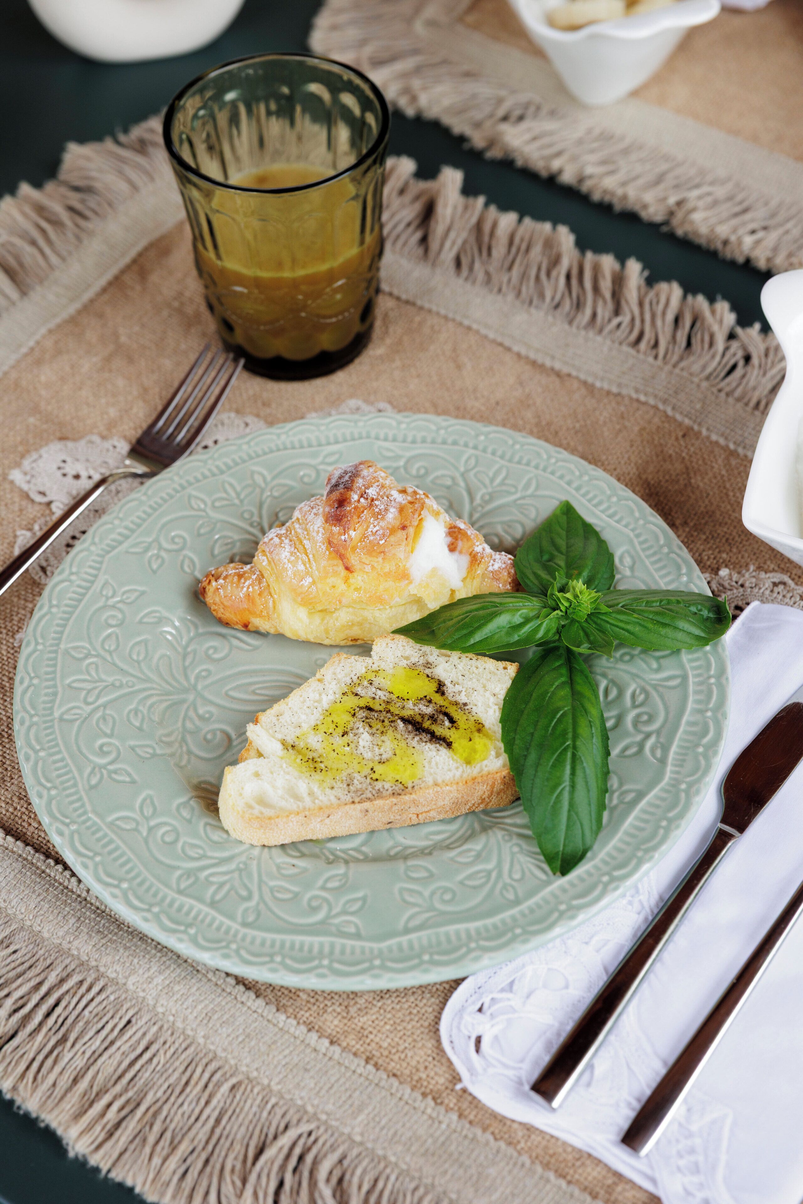 A plate with food and a glass of beverage on a table with a napkin and utensils.