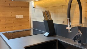 Une cuisine moderne avec un robinet noir élégant, une cuisinière intégrée et un panneau mural en bois.