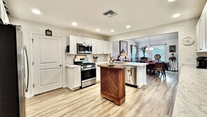 A modern kitchen with white cabinetry, stainless steel appliances, and a wooden island.