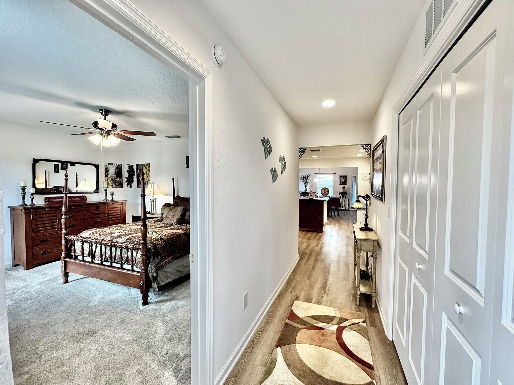 A hallway with a bed, dresser, and a ceiling fan in a bedroom.