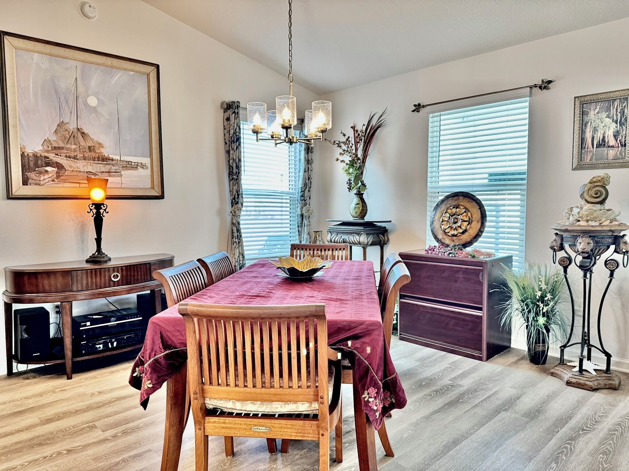 Un coin repas avec une table en bois, des chaises, un lustre et un tableau au mur.
