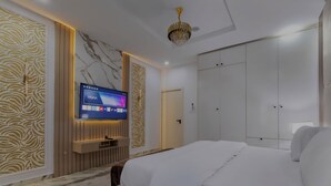 Una camera d'hotel moderna con un letto grande, una TV a parete e un armadio.