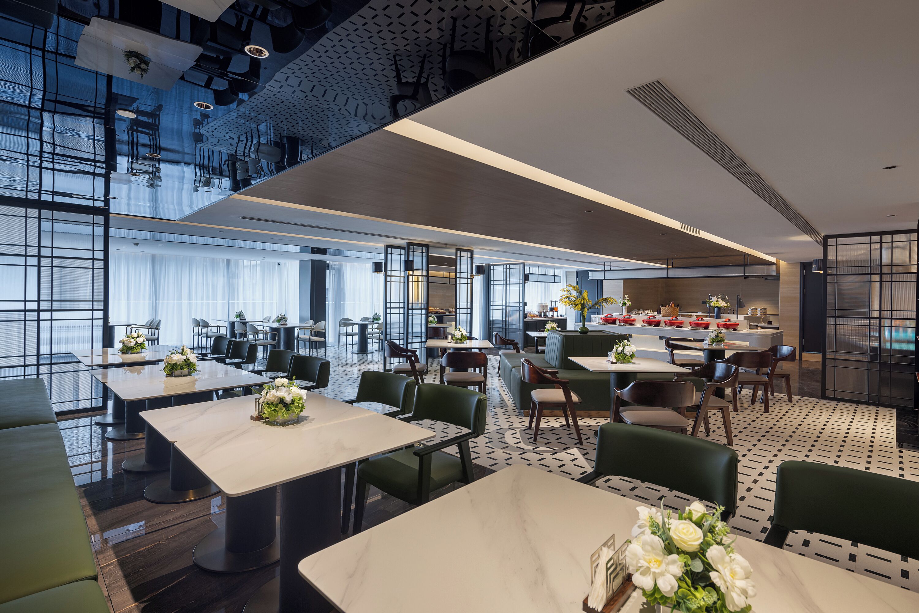 A modern dining area with tables and chairs, a kitchen area, and a seating area with a view of the city.