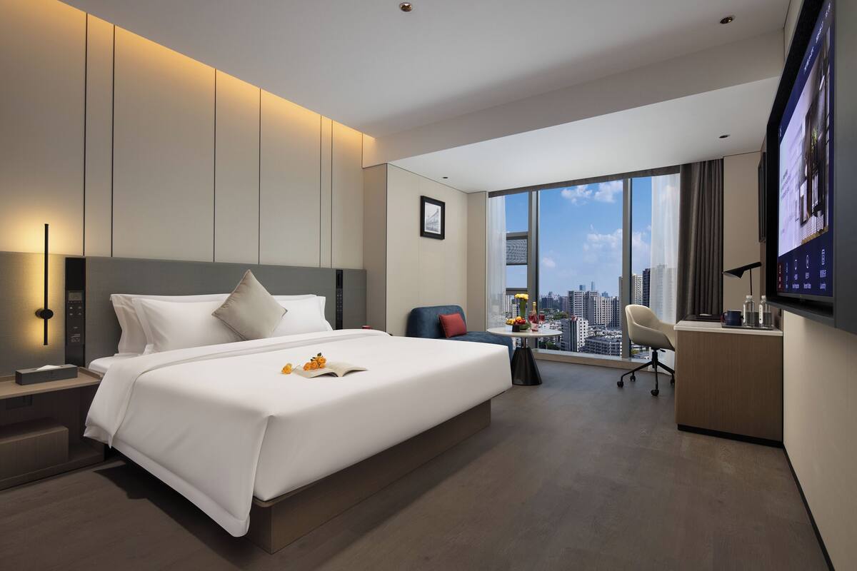 Una habitación de hotel moderna con una cama grande, un escritorio y vistas a la ciudad.