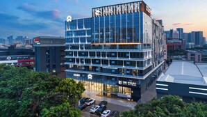 A modern hotel with multiple floors, large windows, and a parking lot in front. - Guangzhou Sylvien Apricity Hotel (Guangzhou)