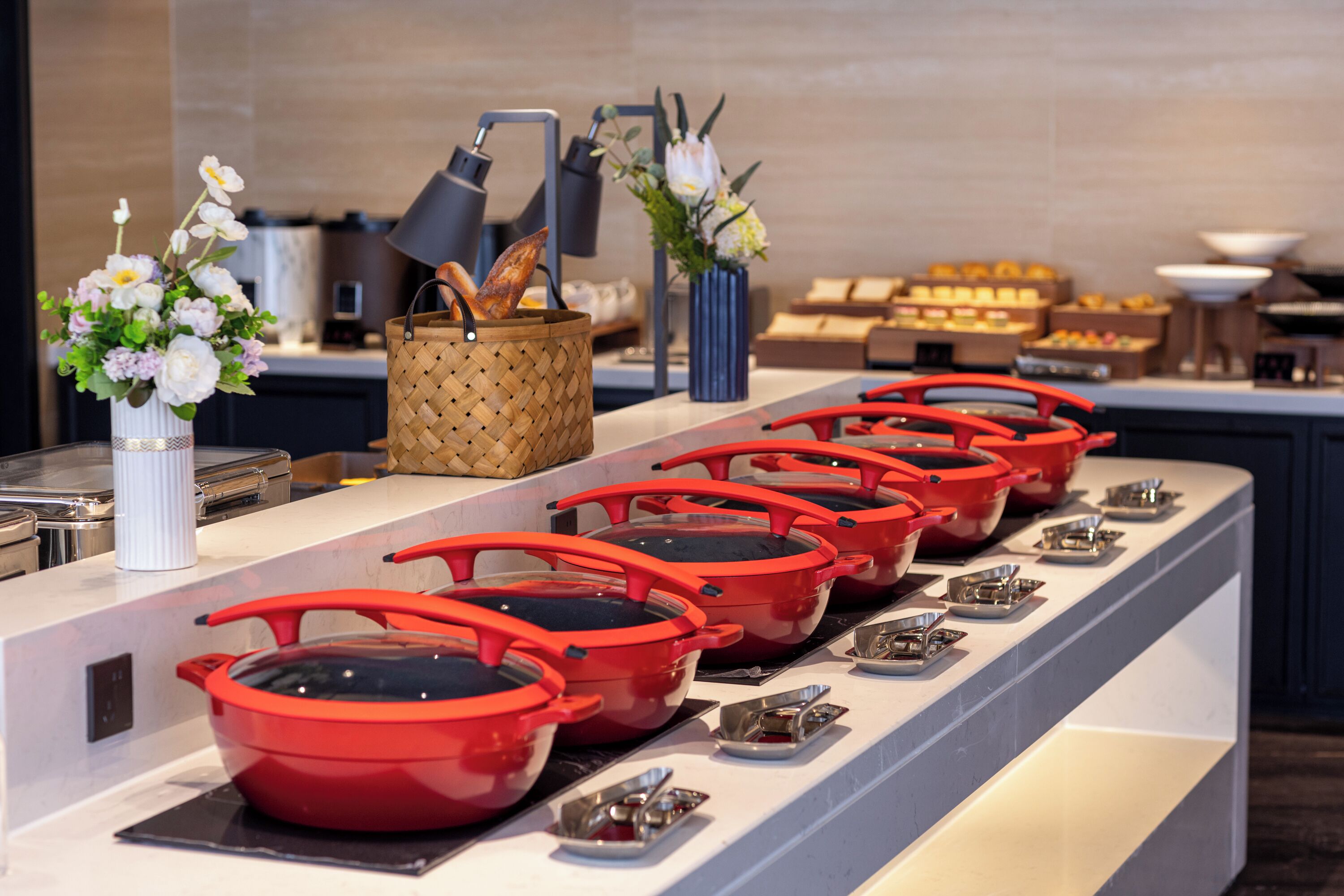 Un montaje de buffet con varios cuencos rojos y pequeños recipientes metálicos sobre una barra.