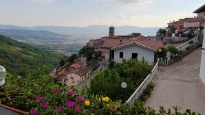 Un pueblo en la ladera de una colina con casas escalonadas, cielo despejado y vistas a montañas distantes.