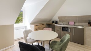 Una cocina moderna con comedor, que incluye una mesa blanca, sillas y horno empotrado.