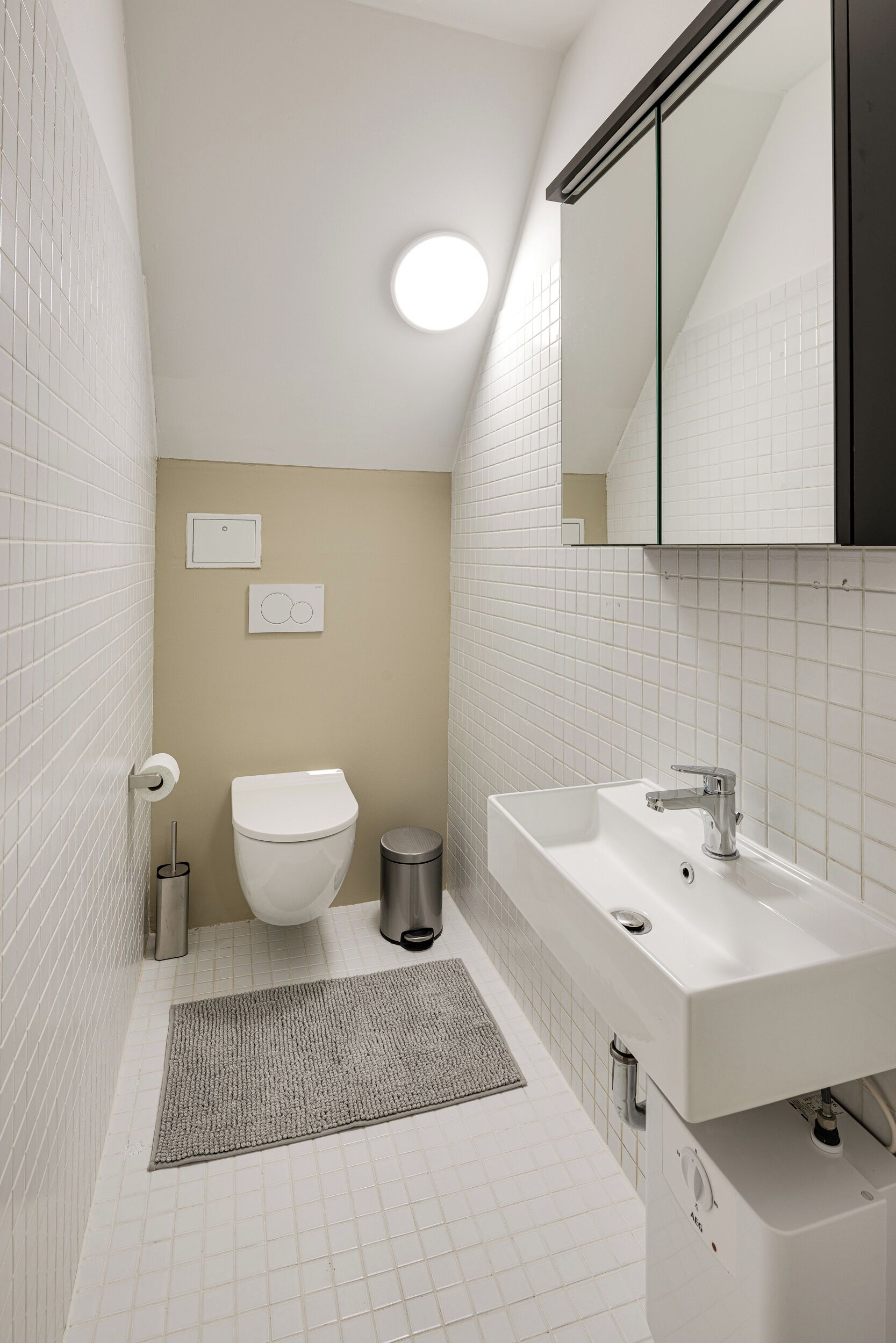 A modern bathroom with a toilet, sink, and mirror.